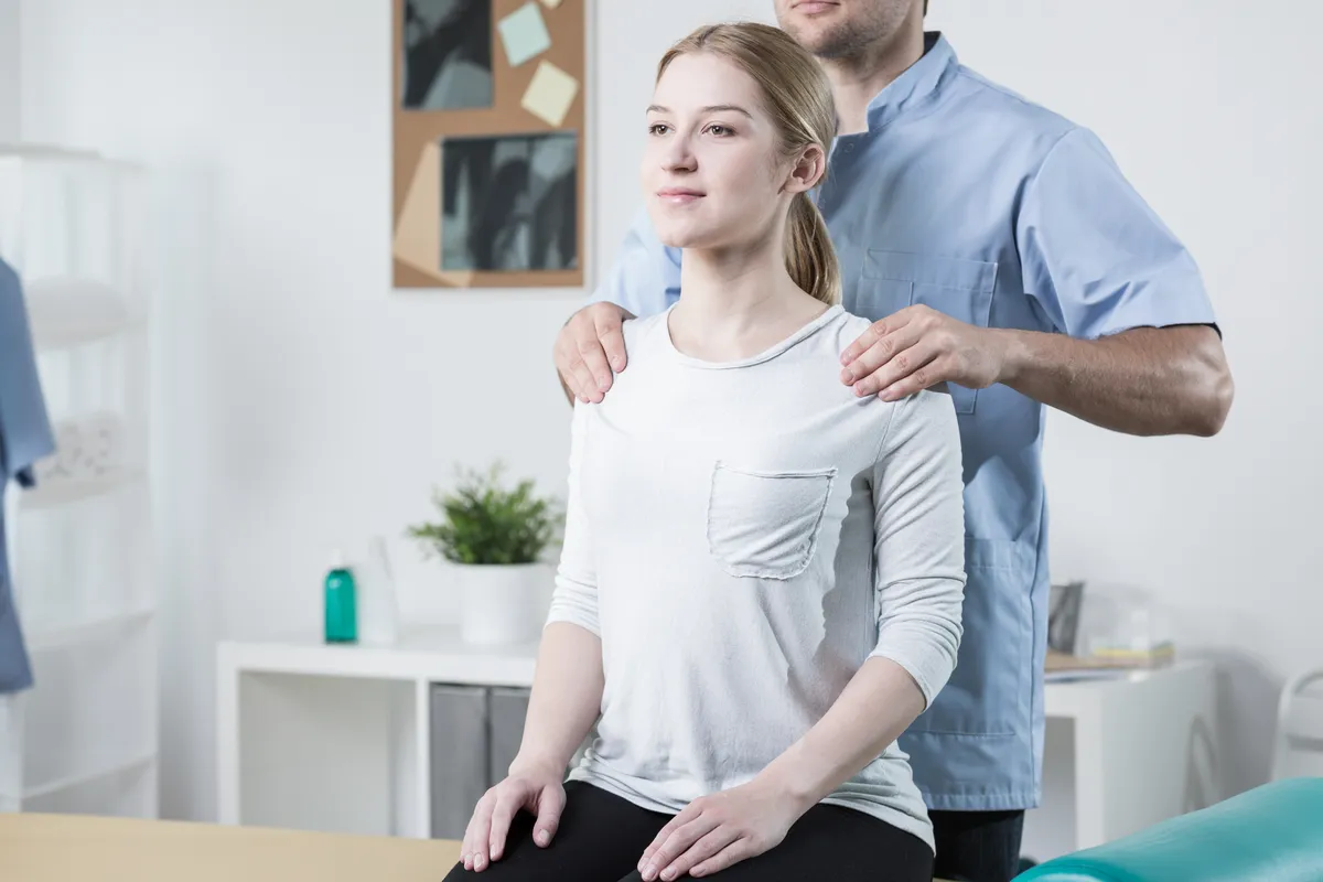 Image of physical therapist helping female patient with back pain