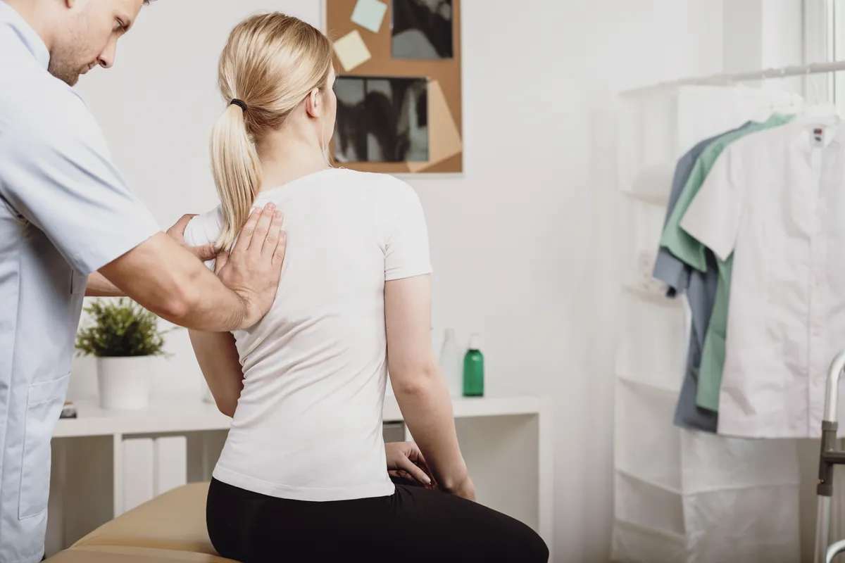 Professional doctor examining woman with a crooked spine during physiotherapy