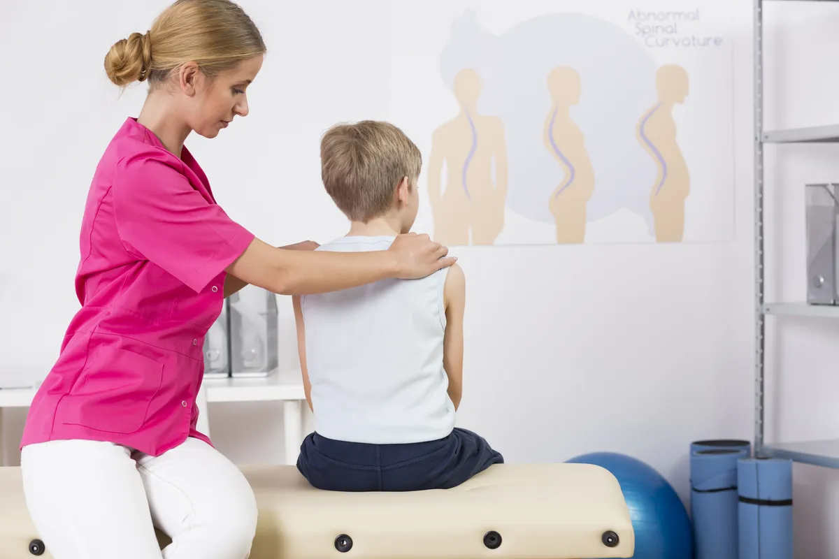 Physiotherapist correcting body posture of a small boy