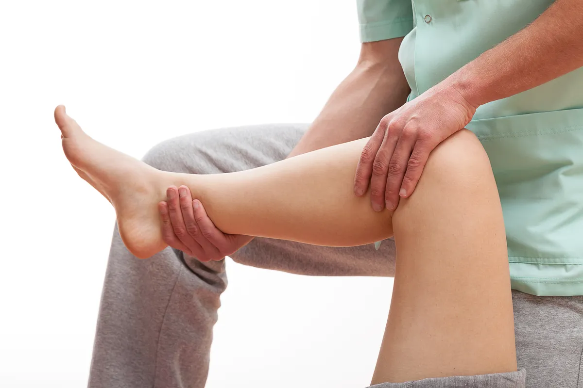 Doctor is stretching woman leg on physiotherapy session