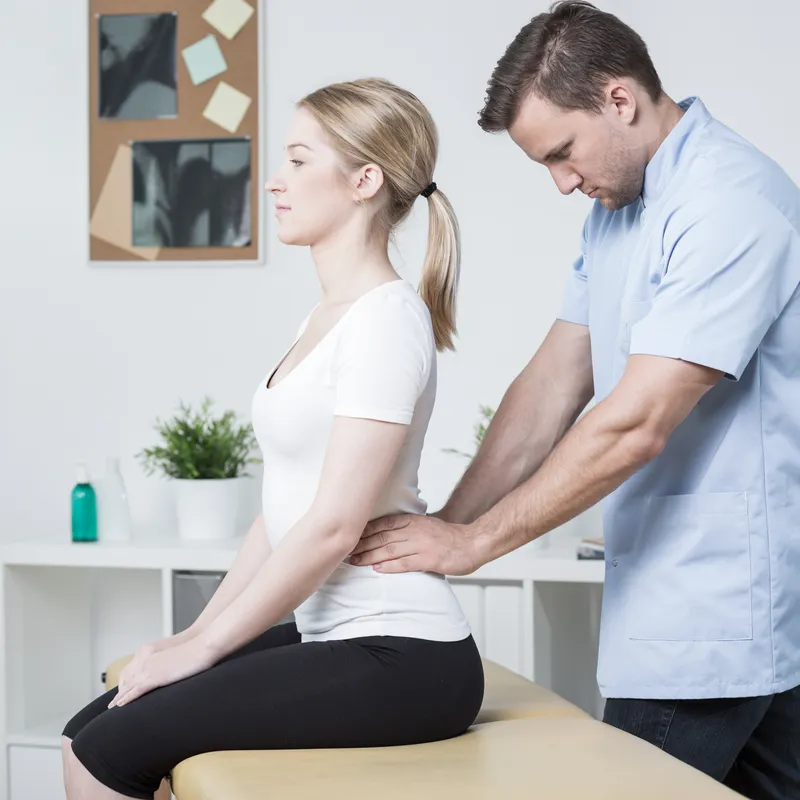 Young physiotherapist doing lumbar spine mobilization