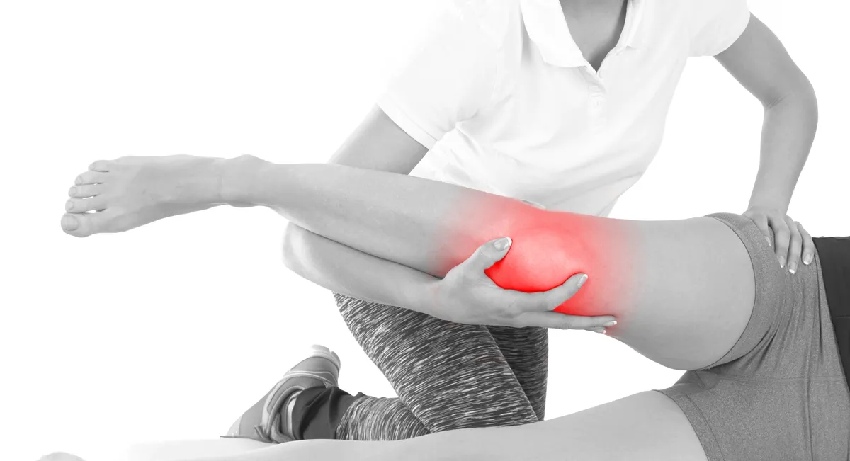Doctor is stretching woman leg on physiotherapy session.