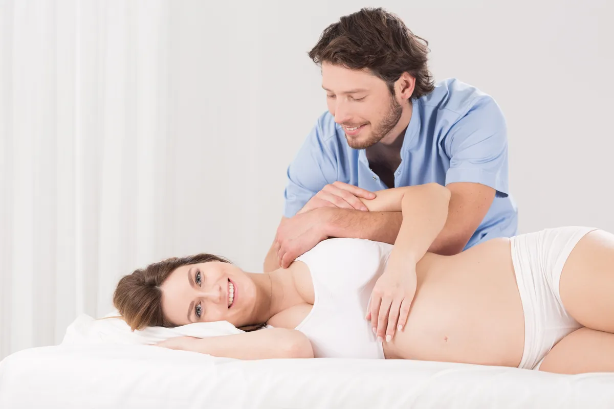 Happy pregnant woman and shoulder exercises with physiotherapist
